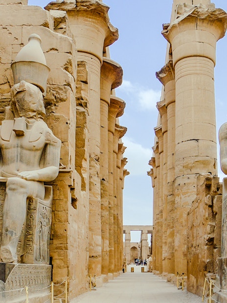 Giant statues at Karnak Temple in Luxor, Egypt, flanked by ancient columns.