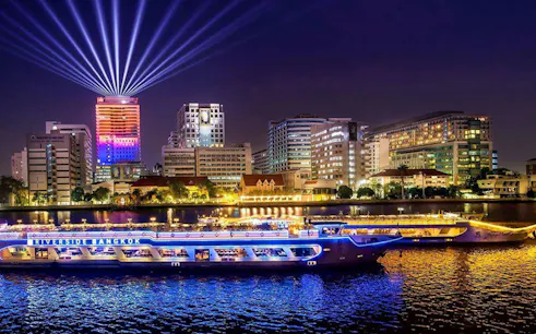 Riverside Carnival Cruise on Chao Phraya River with Bangkok skyline at night.
