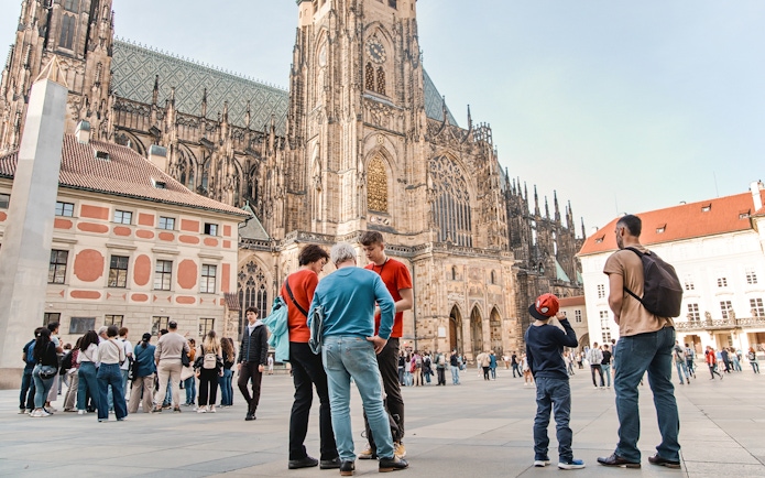 Tourists gather in front of Prague Castle during a guided tour in Prague Old Town.