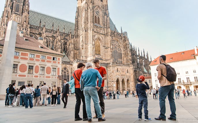 Tourists gather in front of Prague Castle during a guided tour in Prague Old Town.