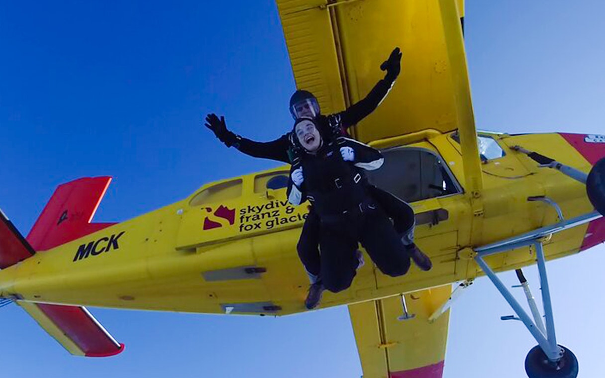 Skydivers jumping from a plane over Franz Josef Glacier, New Zealand.