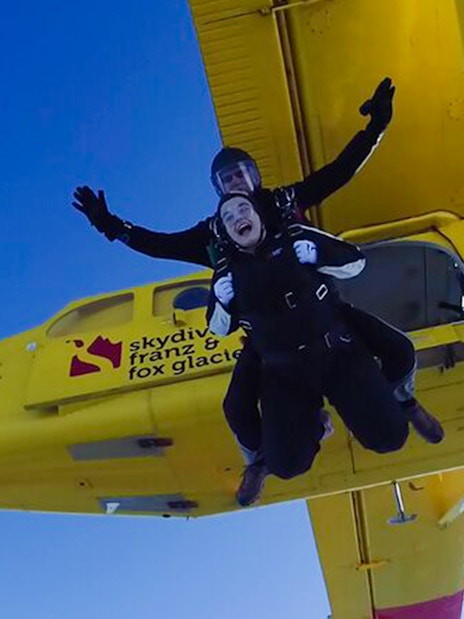 Skydivers jumping from a plane over Franz Josef Glacier, New Zealand.