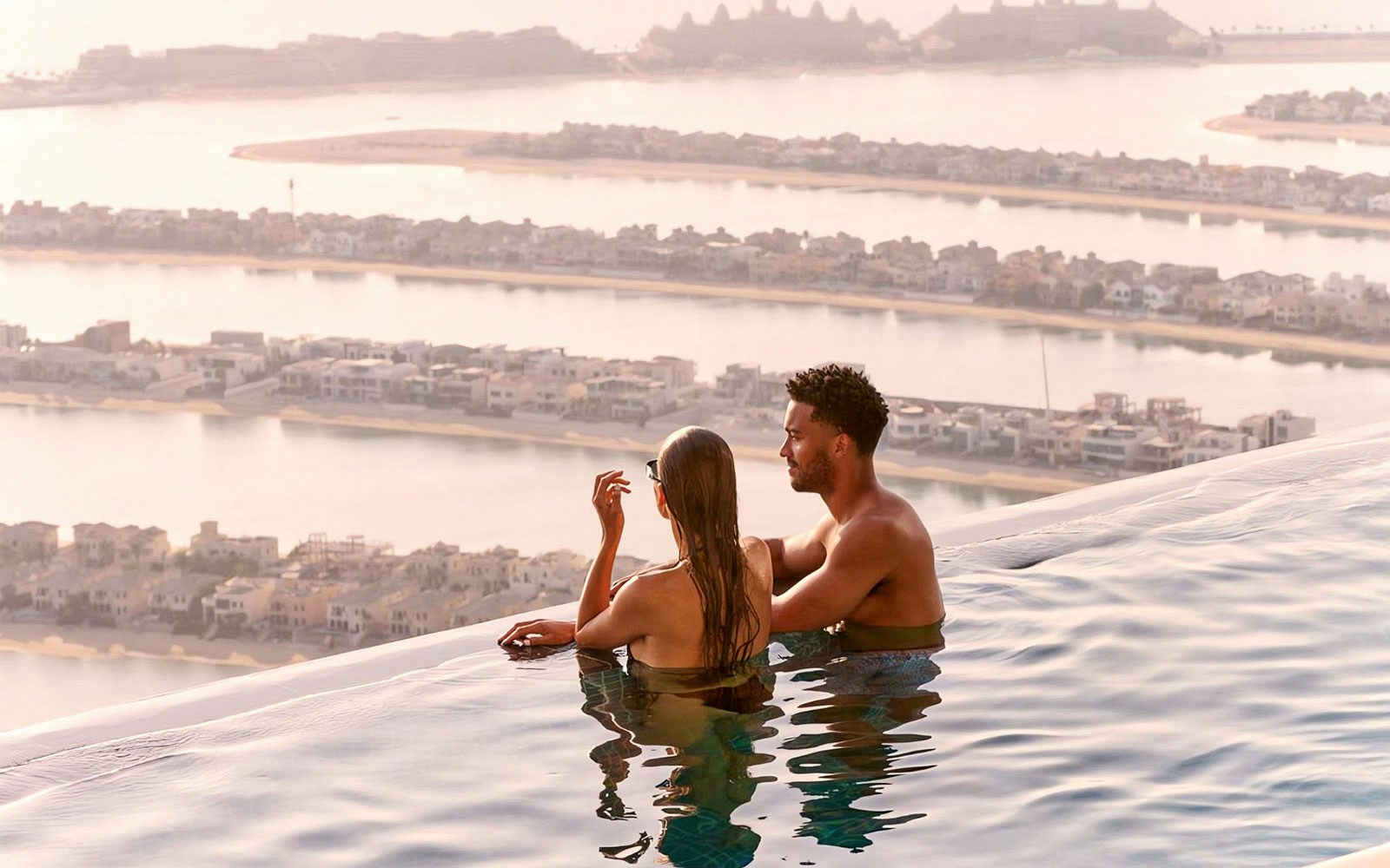 Couple enjoying the view from AURA Sky Pool overlooking Palm Jumeirah, Dubai.
