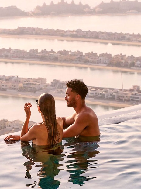 Couple enjoying the view from AURA Sky Pool overlooking Palm Jumeirah, Dubai.