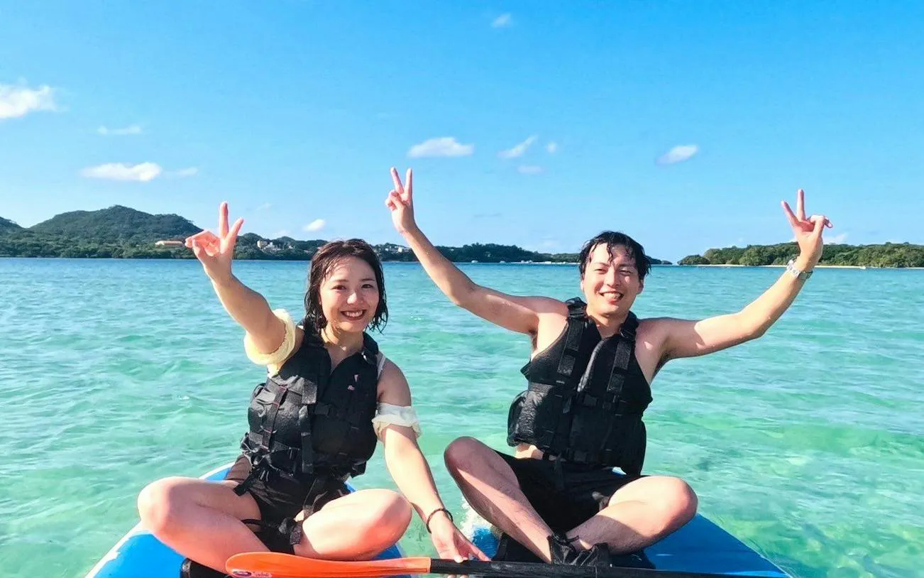 Two people enjoying a SUP tour on clear waters near Ishigaki's Phantom Island, Okinawa.