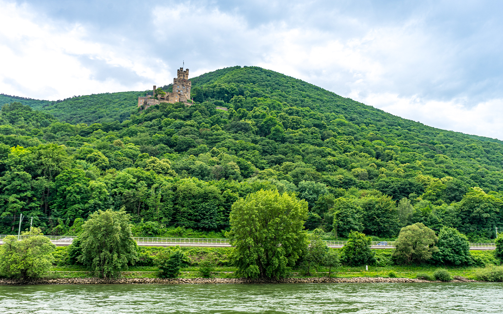 Castle on a hill in the Middle Rhine Valley, Germany, surrounded by lush greenery.