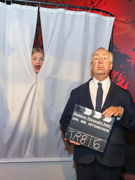 Wax figure of Alfred Hitchcock holding a clapperboard at Madame Tussauds Vienna.