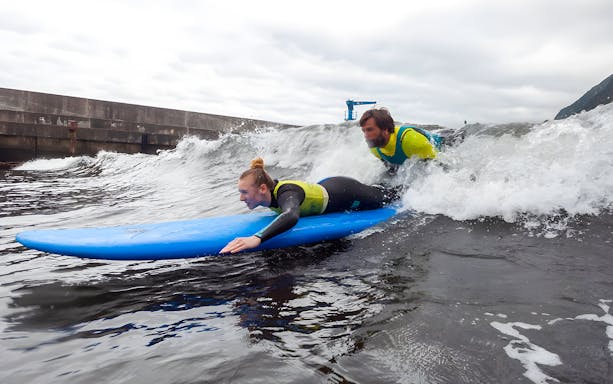 Surfer and instructor riding a wave during a private surf lesson at Madeira Island.