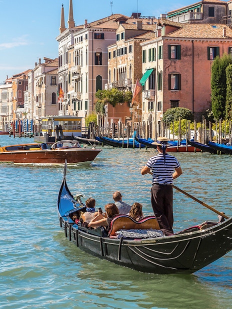 Gondola on Venice's Grand Canal with historic buildings in the background.