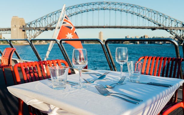 Table set for lunch on a catamaran with Sydney Harbour Bridge in the background.