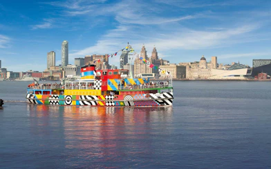 Colorful Mersey Ferry on the River Mersey with Liverpool skyline in the background.