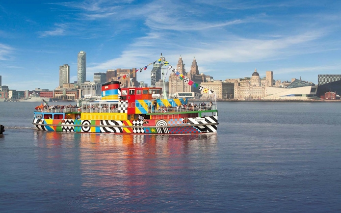 Colorful Mersey Ferry on the River Mersey with Liverpool skyline in the background.