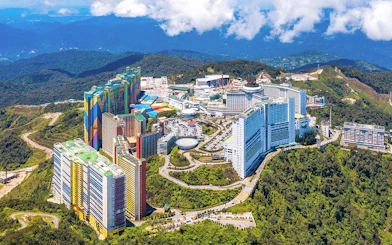 Aerial view of Genting Highlands resort complex surrounded by lush green hills.