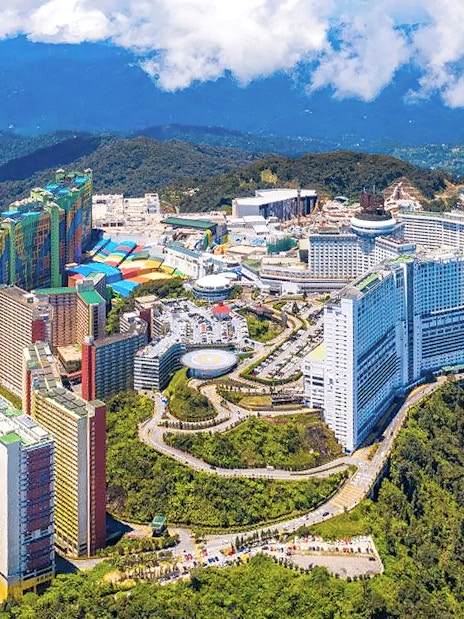 Aerial view of Genting Highlands resort complex surrounded by lush green hills.