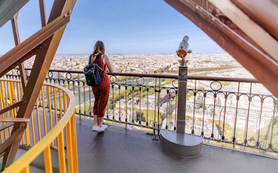 Visitor admiring Paris skyline from second floor of Eiffel Tower.