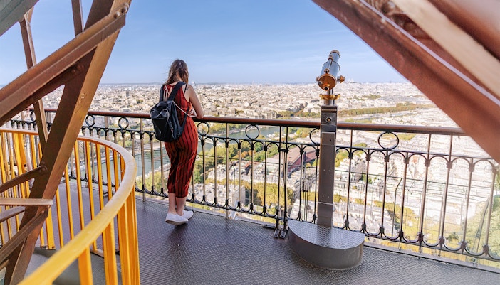 Visitor overlooking Paris from Eiffel Tower's second floor.