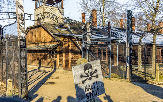 Auschwitz-Birkenau entrance gate with warning sign, part of guided tour from Krakow.