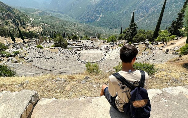 Visitors overlooking the ancient theater at Delphi Archaeological Site, Greece.