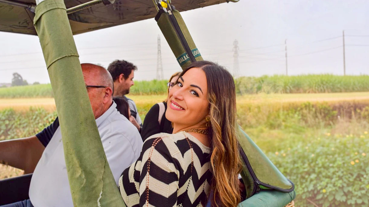 Passengers preparing for a hot air balloon ride in Luxor, Egypt, with green fields in the background.