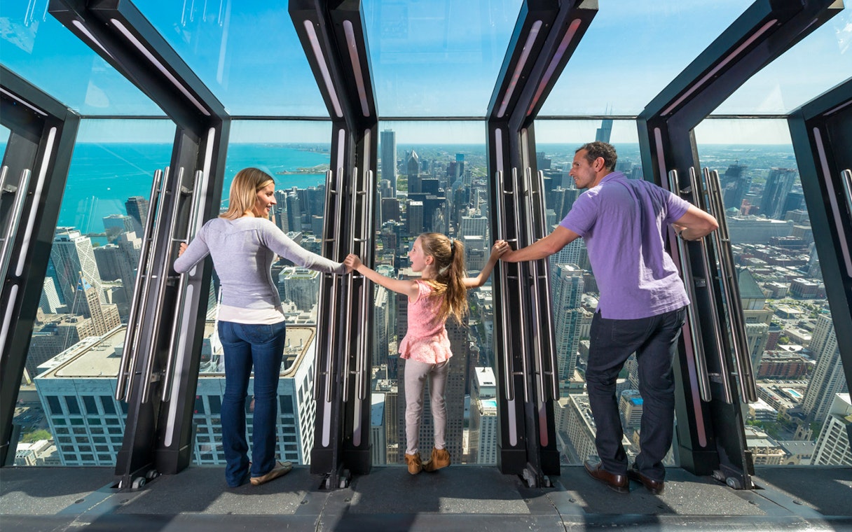 Family enjoying the view from Chicago's Skydeck with city skyline in the background.