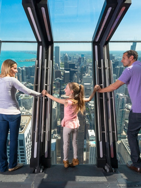 Family enjoying the view from Chicago's Skydeck with city skyline in the background.