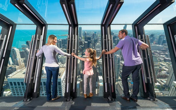 Family enjoying the view from Chicago's Skydeck with city skyline in the background.
