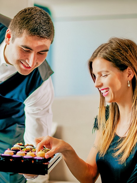 Server presenting cupcakes to a woman at Burj Khalifa cafe.