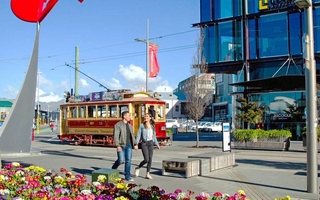 Couple walking near historic tram in Christchurch city center.
