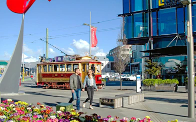 Couple walking near historic tram in Christchurch city center.