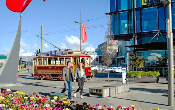 Couple walking near historic tram in Christchurch city center.