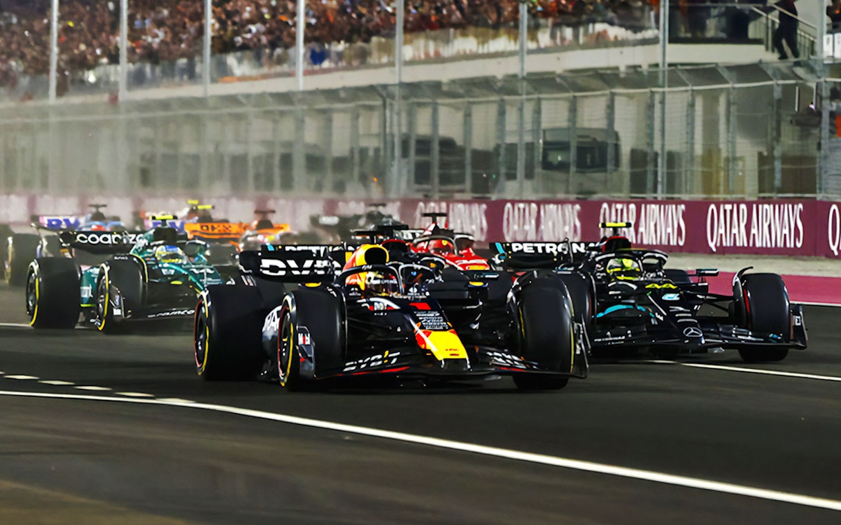 Race cars competing at F1 Qatar Grand Prix on a night track.