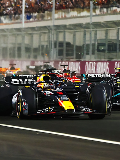 Race cars competing at F1 Qatar Grand Prix on a night track.