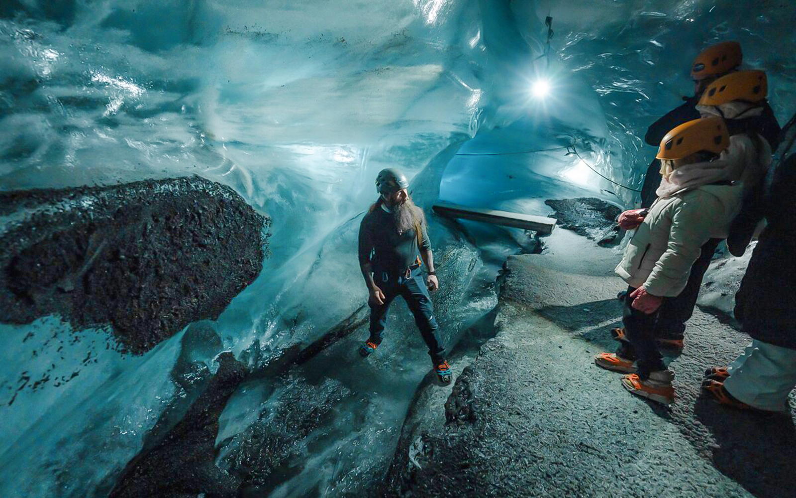 Tour guide assisting guests inside Katla Ice Cave, Iceland.