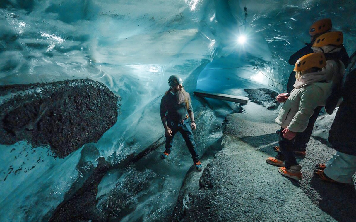 Tour guide assisting guests inside Katla Ice Cave, Iceland.