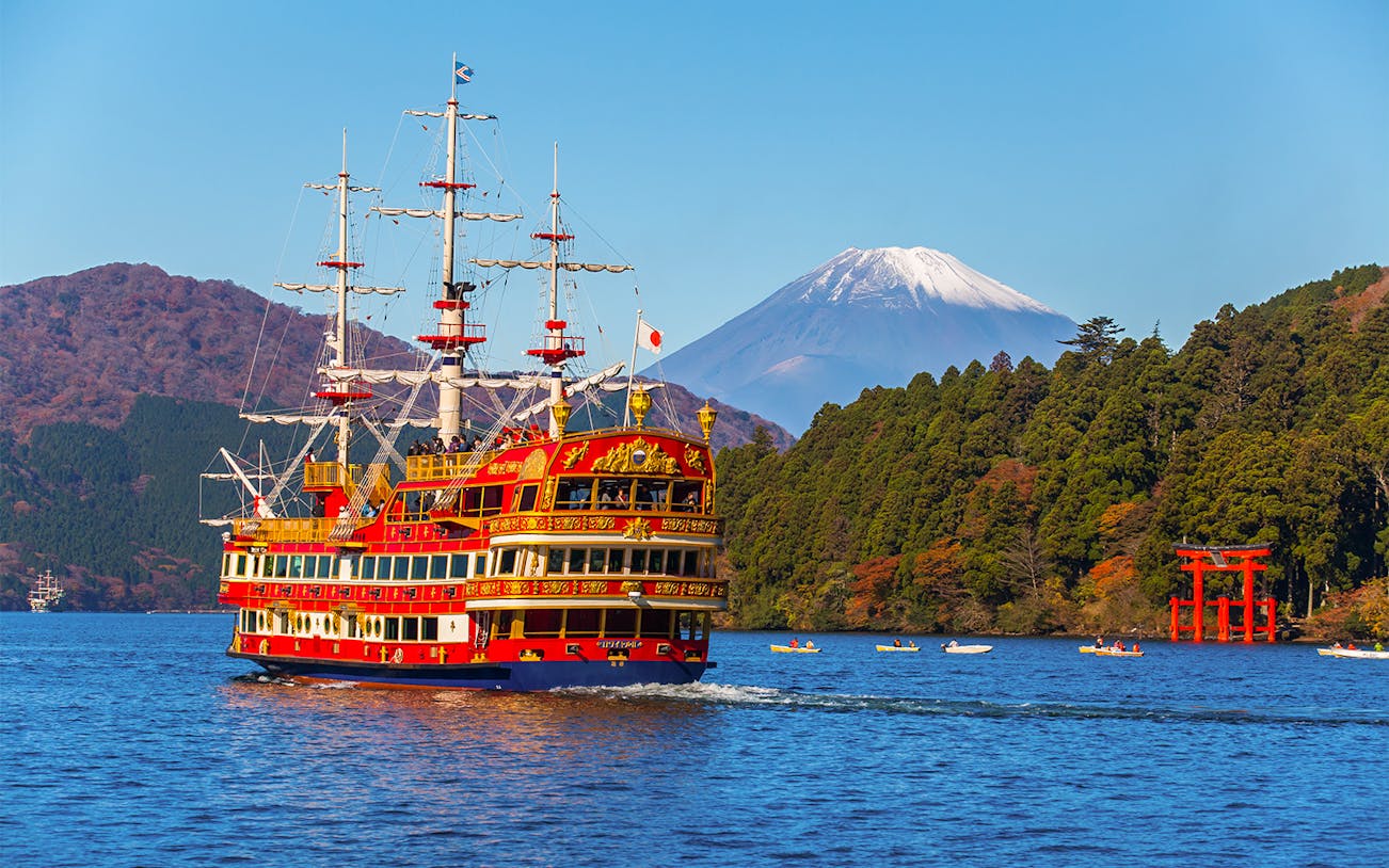 Cruise ship on Lake Ashi with Mt. Fuji and red torii gate in the background.