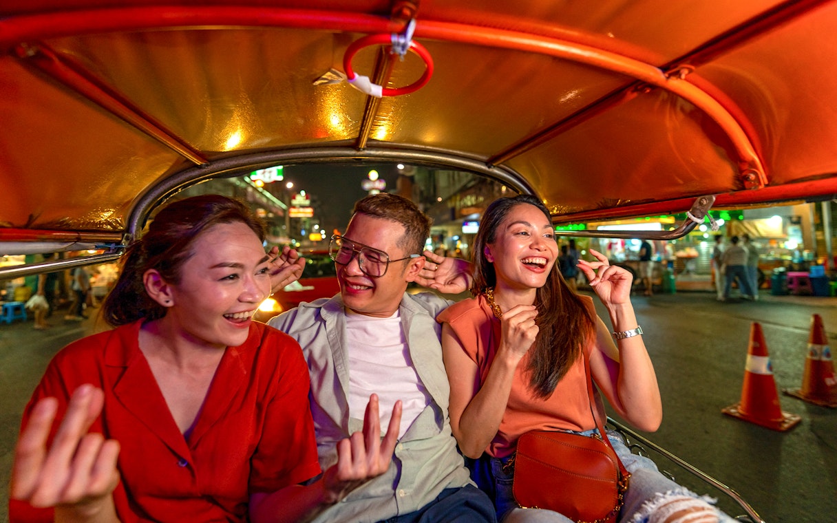 People enjoying a tuk tuk ride at night in Bangkok.
