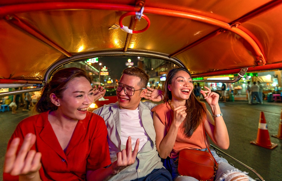 Tuk tuk ride through Bangkok's vibrant streets at night with people exploring Chinatown.