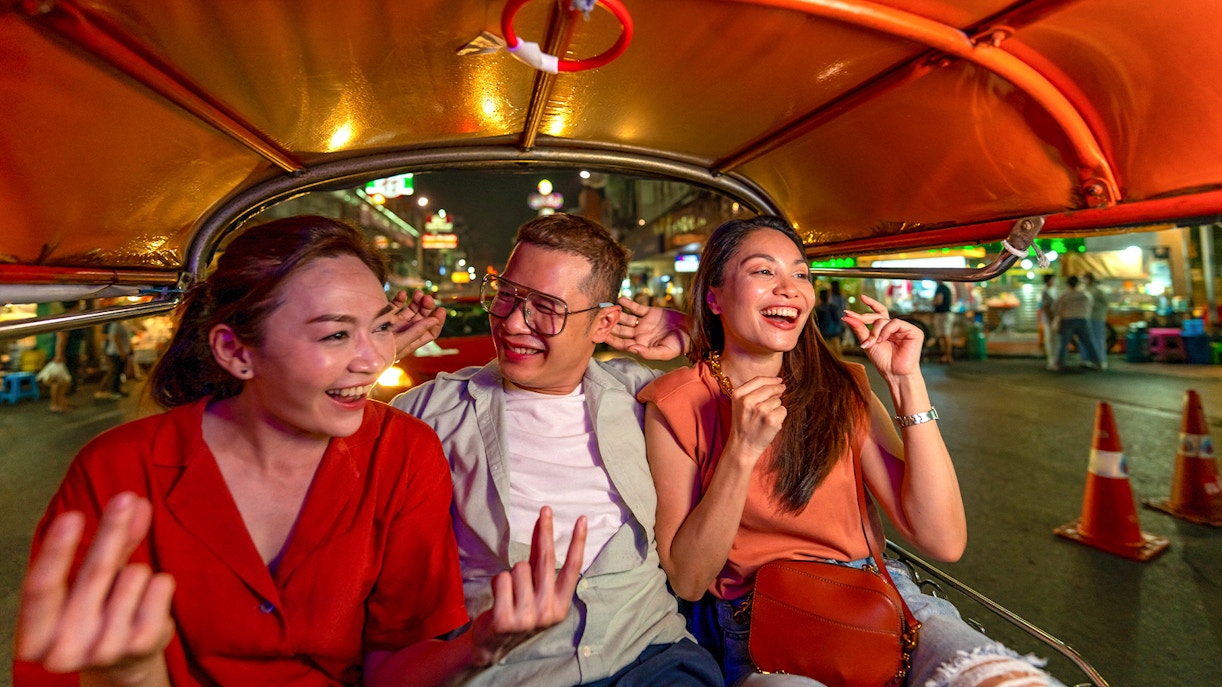 Tuk tuk ride through Bangkok's vibrant streets at night with people exploring Chinatown.