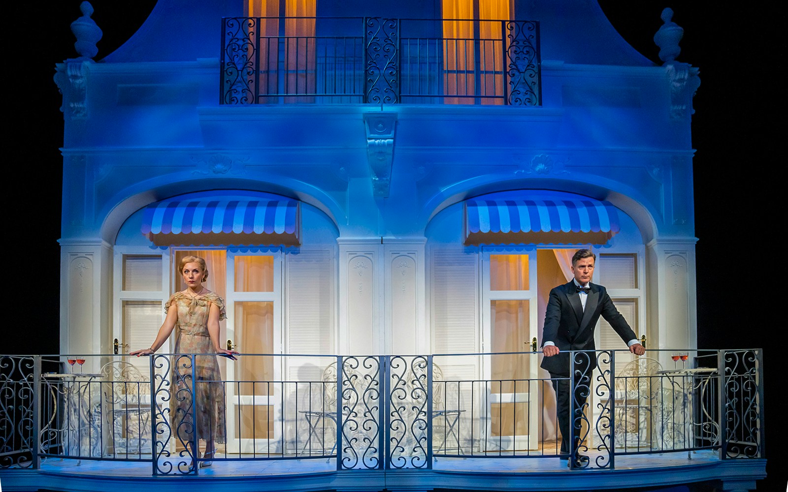 Two actors on a balcony set from the play "Private Lives" in a theater production.