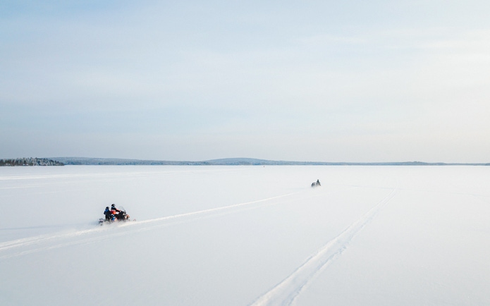 Aerial view of snowmobiles crossing a snowy landscape in Lapland.
