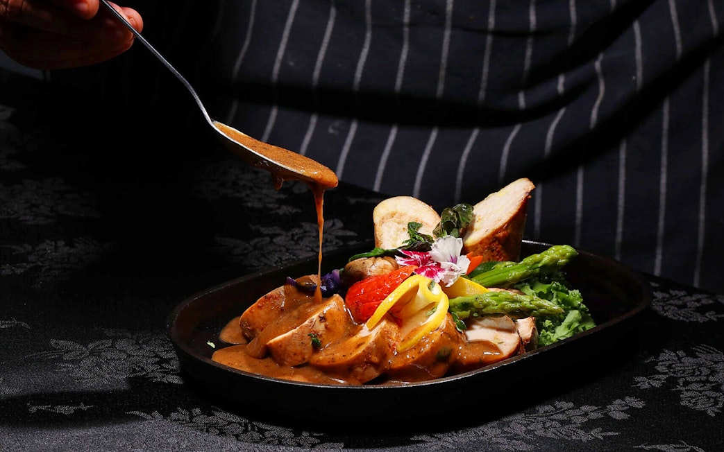 Chef adding sauce to a dish at ARAS restaurant, KL Tower, Kuala Lumpur.