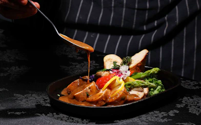 Chef adding sauce to a dish at ARAS restaurant, KL Tower, Kuala Lumpur.