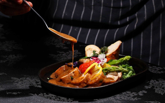 Chef adding sauce to a dish at ARAS restaurant, KL Tower, Kuala Lumpur.