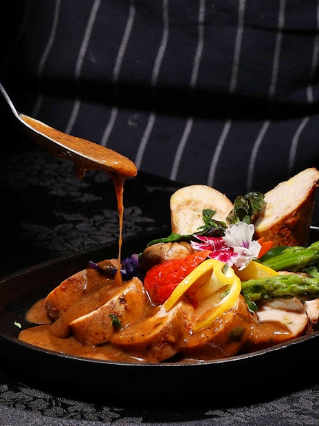 Chef adding sauce to a dish at ARAS restaurant, KL Tower, Kuala Lumpur.