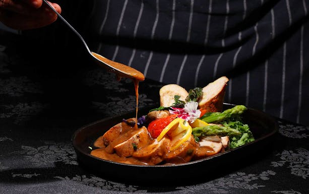 Chef adding sauce to a dish at ARAS restaurant, KL Tower, Kuala Lumpur.