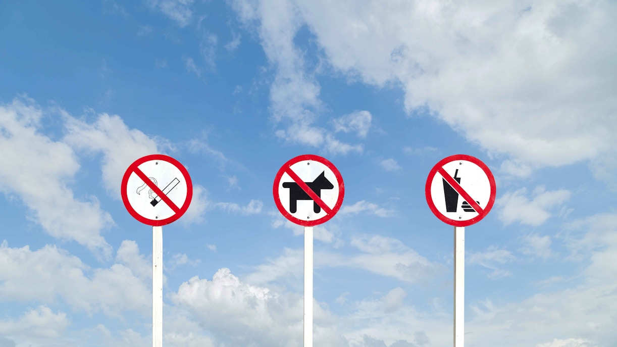 No pets, smoking, or outside food signs against blue sky.