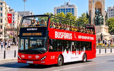 Open-top tour bus in Istanbul near Taksim Square with Republic Monument in the background.