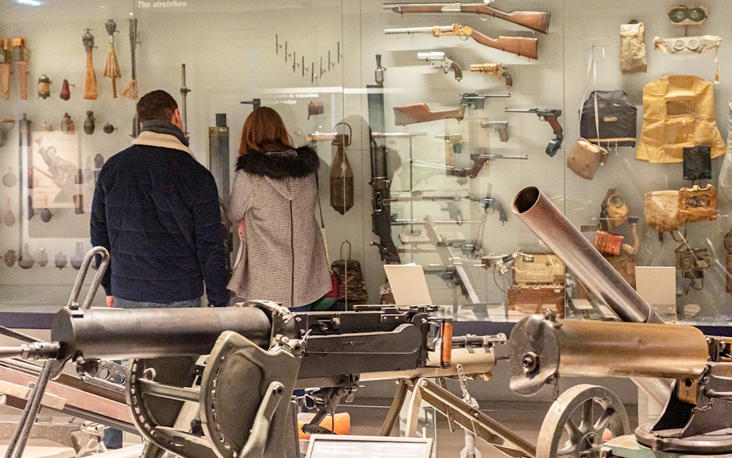 Visitors viewing historical weapons at Paris Army Museum exhibition.