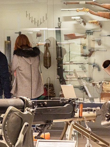 Visitors viewing historical weapons at Paris Army Museum exhibition.