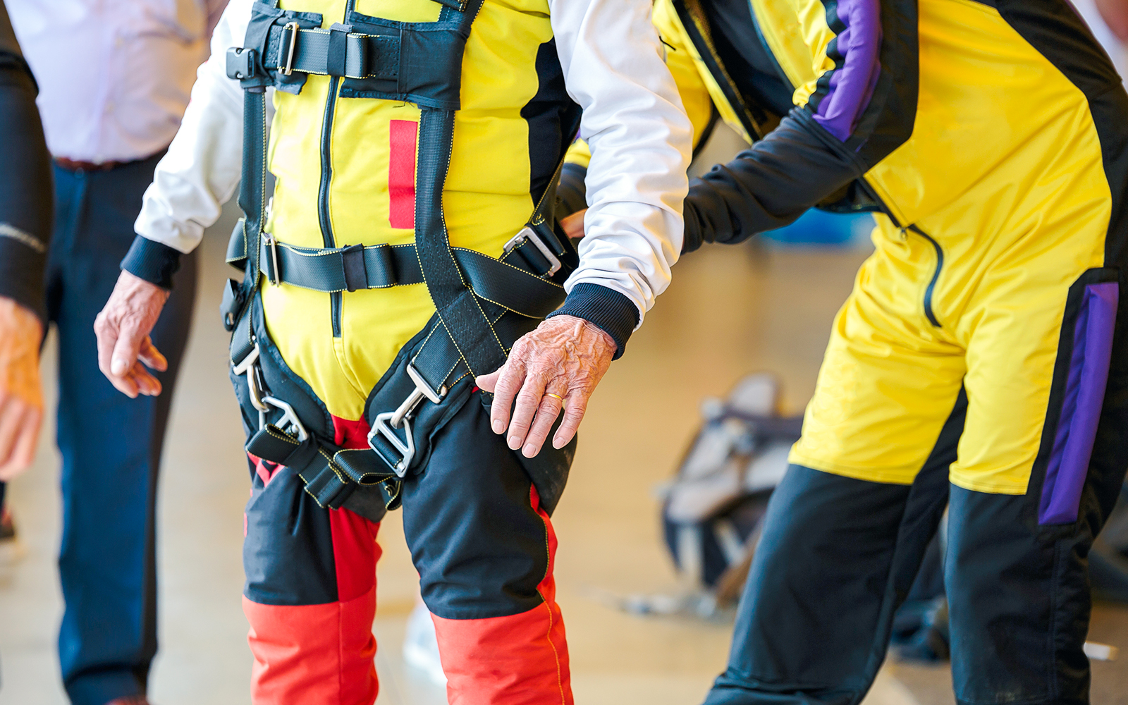 Person inspecting skydiving harness and gear indoors.